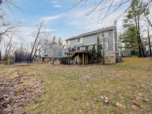 back of house with a yard, a trampoline, a deck, and stairs