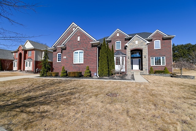 traditional-style home with stone siding, brick siding, and a front yard