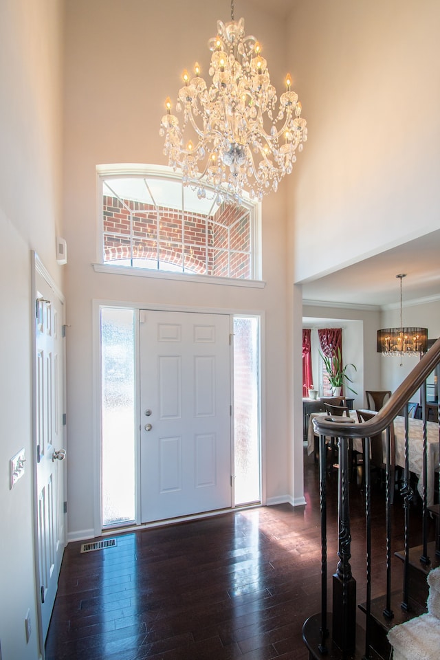 foyer featuring dark wood-style floors, visible vents, stairs, a towering ceiling, and a chandelier