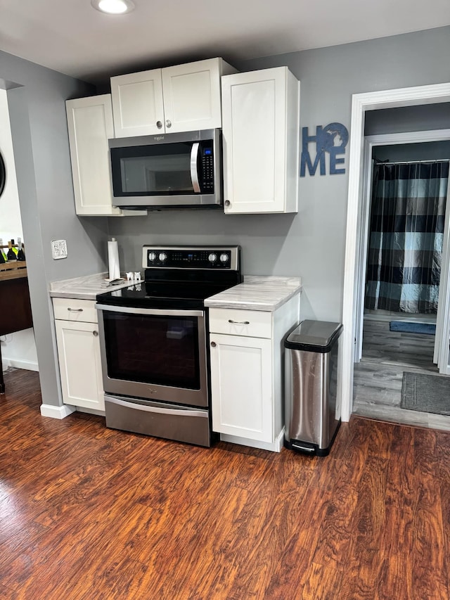 kitchen with stainless steel appliances, light countertops, white cabinetry, and dark wood-style floors