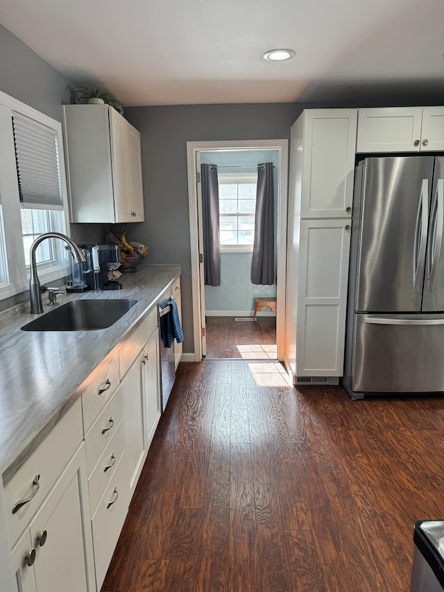 kitchen featuring dark wood-style flooring, a sink, baseboards, white cabinets, and appliances with stainless steel finishes