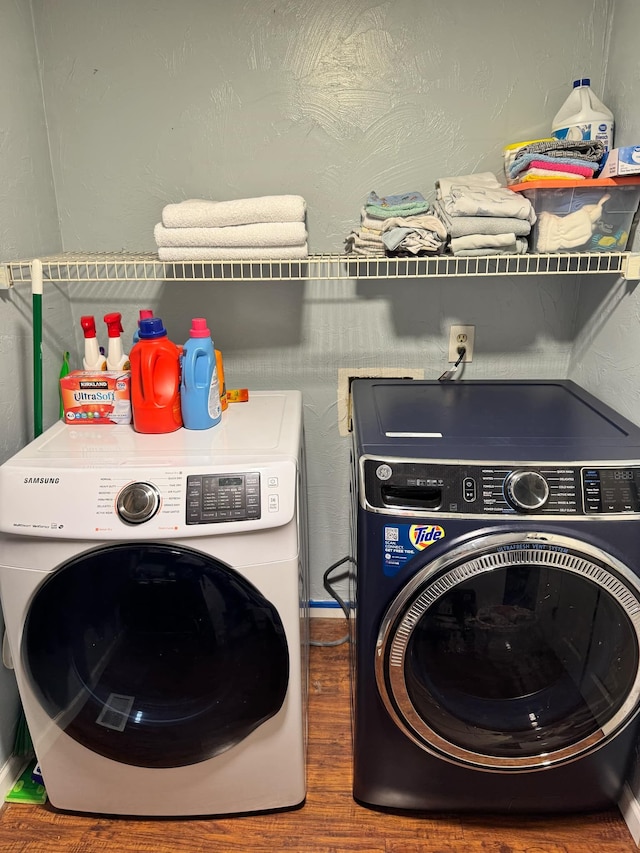 clothes washing area featuring laundry area, wood finished floors, and washer and dryer