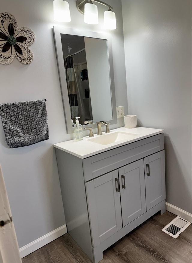 bathroom featuring baseboards, visible vents, wood finished floors, curtained shower, and vanity