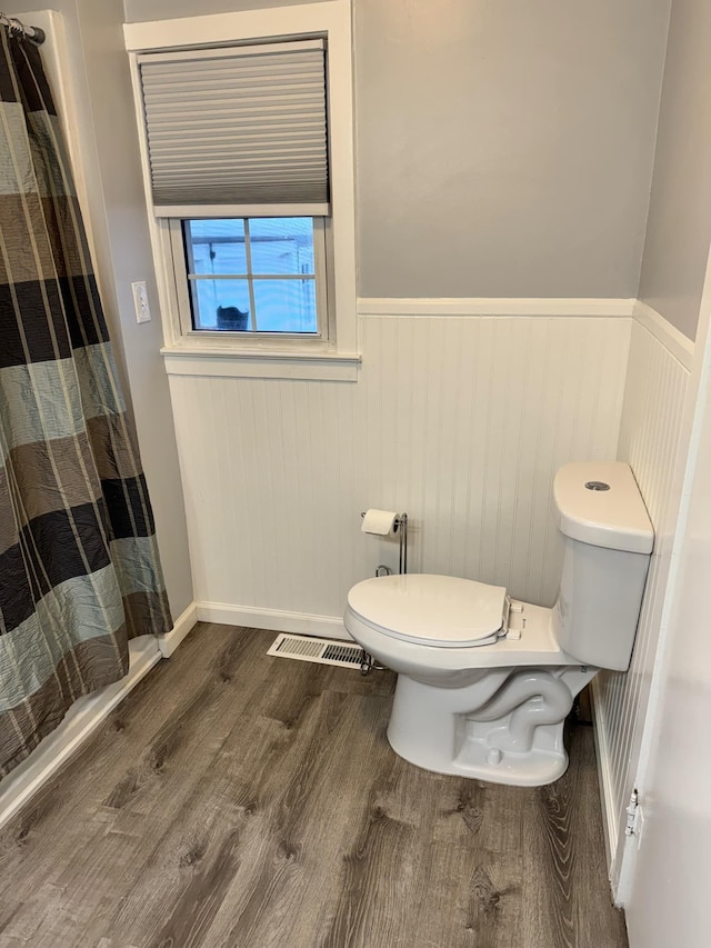 full bath featuring visible vents, toilet, a wainscoted wall, a shower with curtain, and wood finished floors