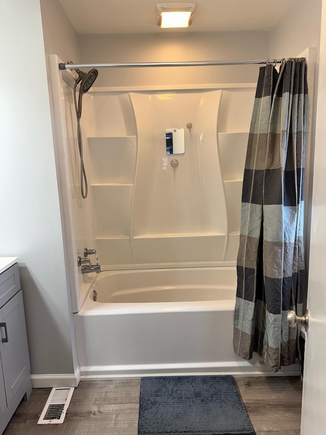 full bath featuring visible vents, shower / bath combo with shower curtain, vanity, wood finished floors, and baseboards