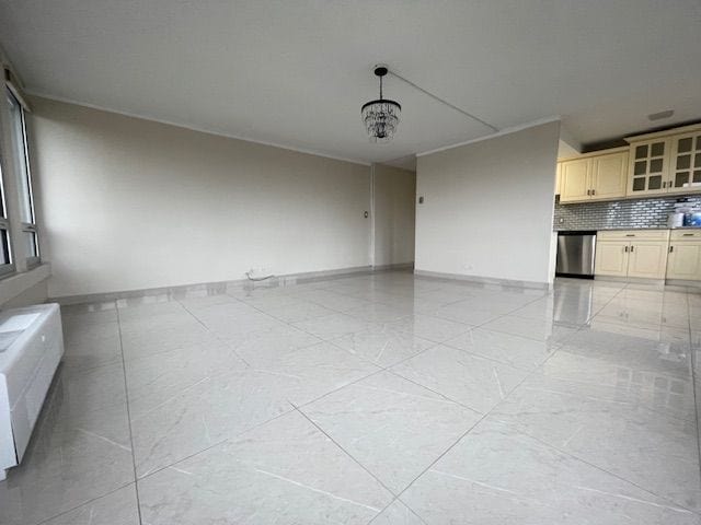 unfurnished living room with a notable chandelier, marble finish floor, radiator heating unit, and baseboards