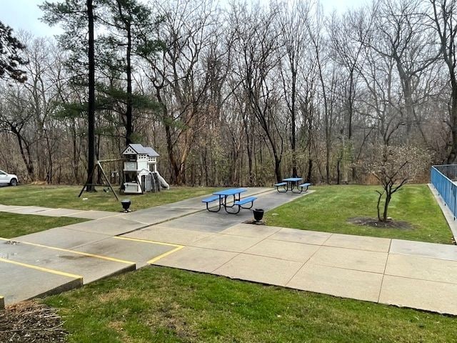 view of community with fence, a lawn, and playground community