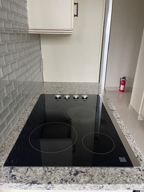 details with backsplash, a fire extinguisher, black electric cooktop, and white cabinetry