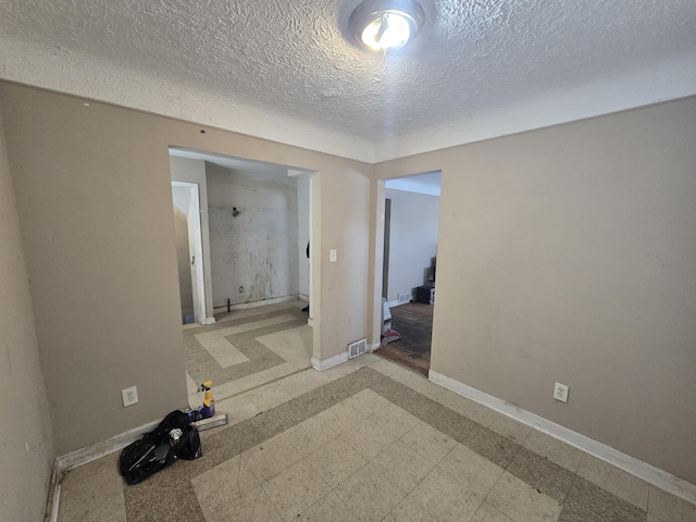 unfurnished bedroom featuring visible vents, a textured ceiling, baseboards, and tile patterned floors