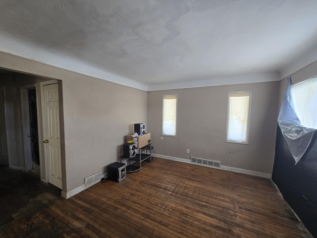 unfurnished office with wood-type flooring, visible vents, and a healthy amount of sunlight