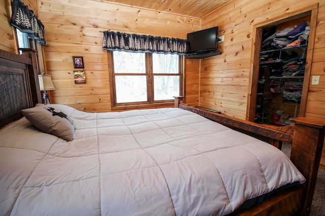 bedroom featuring a walk in closet, a closet, wooden ceiling, and wooden walls