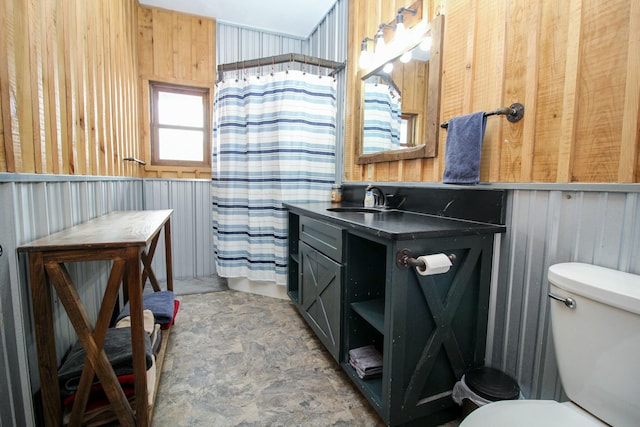 bathroom featuring curtained shower, toilet, a wainscoted wall, wood walls, and vanity