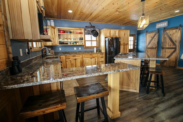 kitchen featuring a barn door, wooden ceiling, dark wood-type flooring, black fridge, and a sink