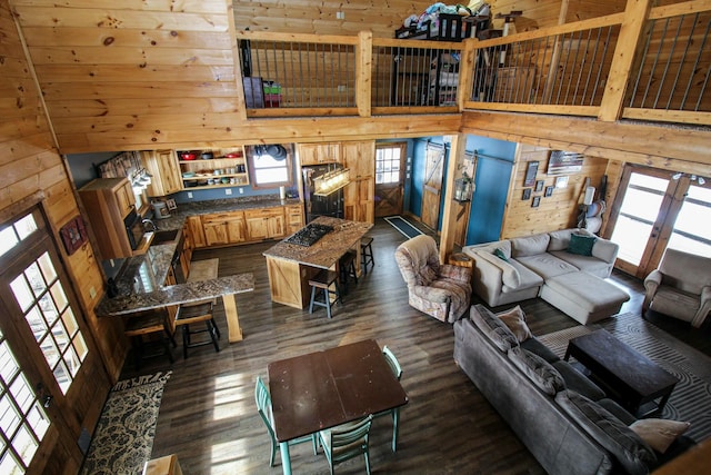 living area featuring dark wood-style floors, a high ceiling, and wood walls