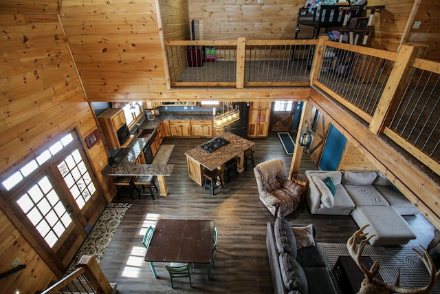 living room with wood walls, dark wood finished floors, and a towering ceiling