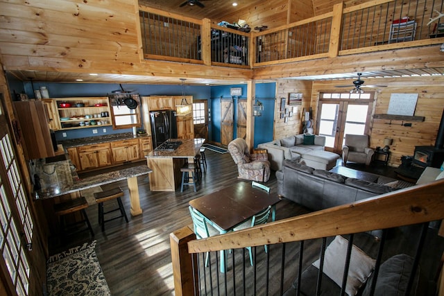 living room with ceiling fan, dark wood-type flooring, a wood stove, and a healthy amount of sunlight