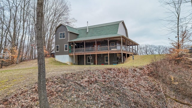 back of house with a deck, a lawn, and a gambrel roof