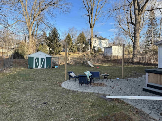 view of yard featuring a shed, a fenced backyard, and an outbuilding