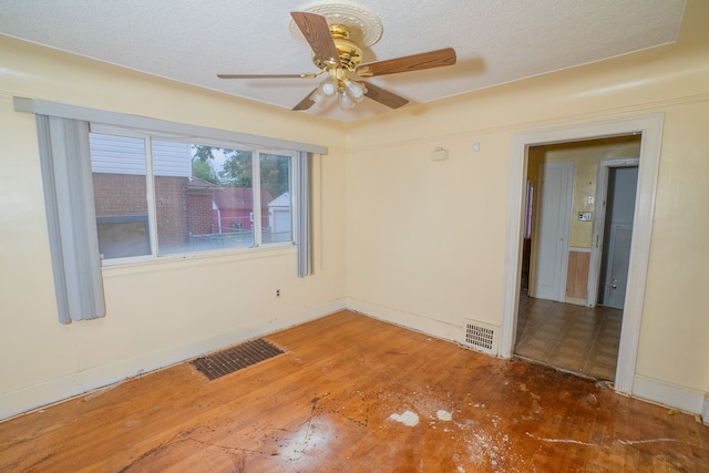 spare room featuring baseboards, wood finished floors, visible vents, and a ceiling fan