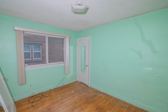 empty room with a textured ceiling and wood finished floors