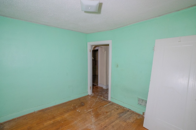 empty room featuring visible vents, a textured ceiling, and wood finished floors