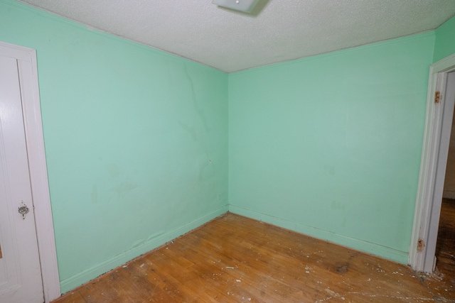 empty room with a textured ceiling, baseboards, and wood finished floors