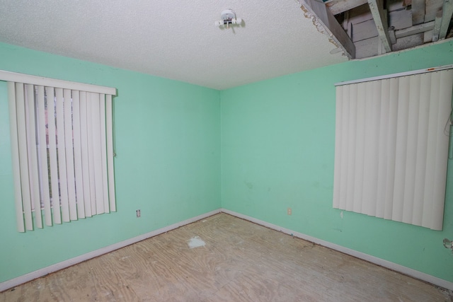 spare room featuring a textured ceiling and baseboards