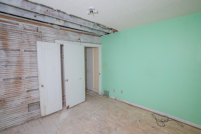 unfurnished bedroom with a textured ceiling, visible vents, and baseboards