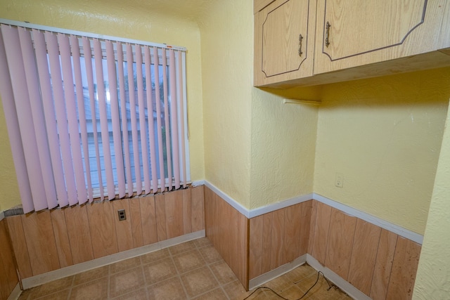 clothes washing area with a textured wall, a wainscoted wall, and wood walls