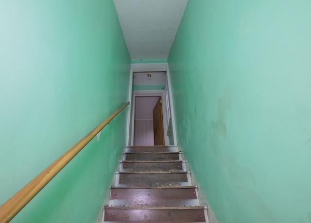 staircase with a textured ceiling