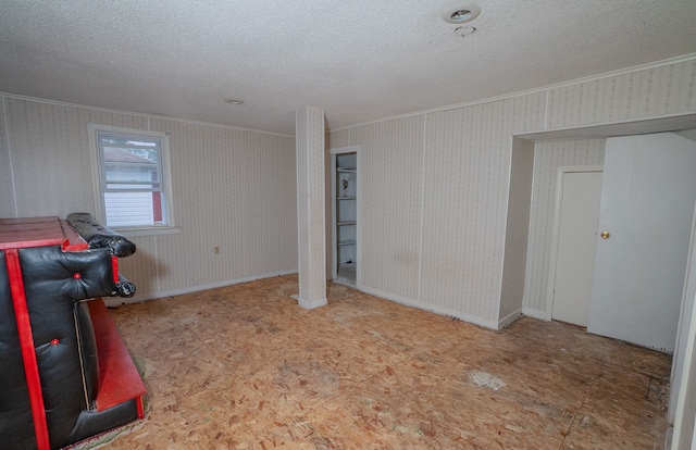 interior space featuring ornamental molding, a textured ceiling, baseboards, and wallpapered walls