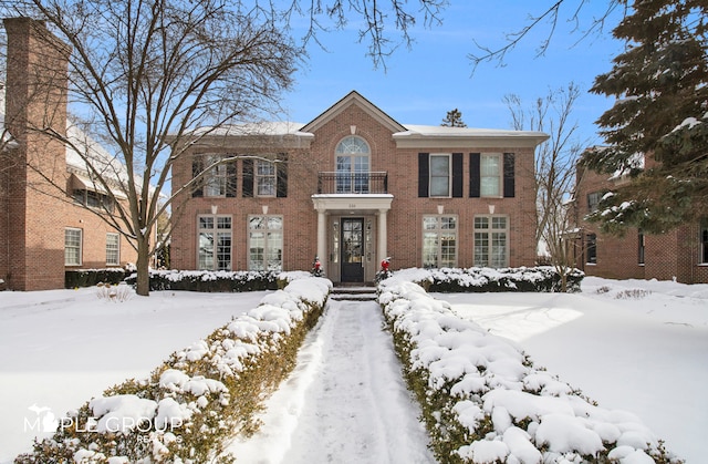 colonial inspired home with brick siding and a balcony