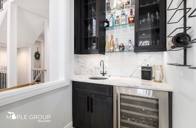 bar featuring tasteful backsplash, beverage cooler, indoor wet bar, and a sink