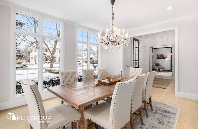 dining area featuring baseboards, light wood-style floors, a chandelier, and crown molding