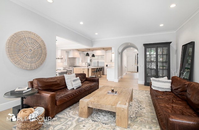 living room with arched walkways, light wood-style floors, recessed lighting, and crown molding