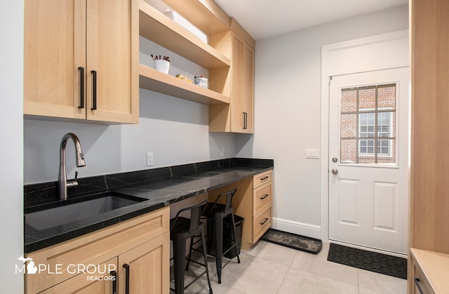 kitchen with light tile patterned floors, open shelves, a sink, and light brown cabinetry