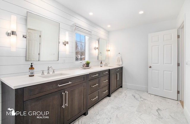 bathroom with double vanity, marble finish floor, a sink, and recessed lighting