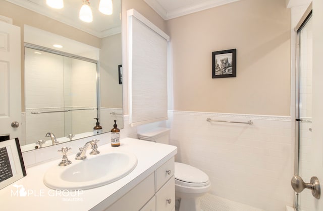 full bath featuring toilet, tile walls, vanity, wainscoting, and crown molding