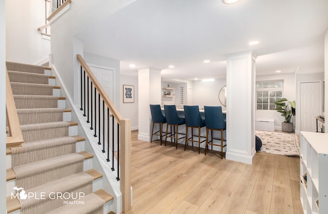 interior space featuring decorative columns, recessed lighting, wood-type flooring, bar, and baseboards