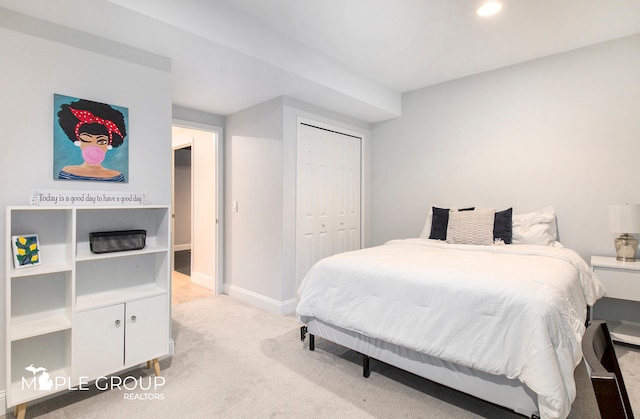 bedroom with baseboards, a closet, and light colored carpet