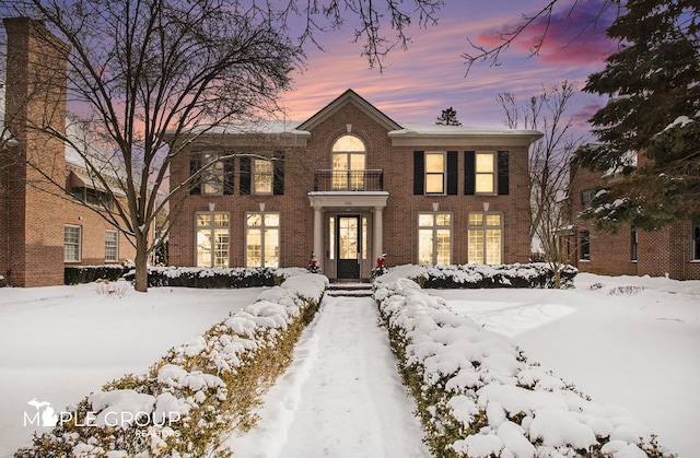 georgian-style home featuring a balcony and brick siding