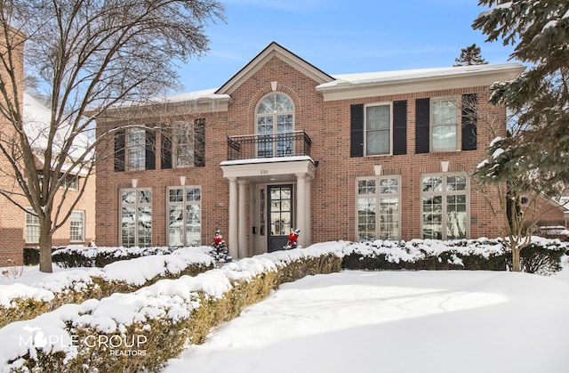 colonial house featuring brick siding and a balcony