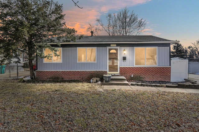 view of front of property featuring a gate, fence, and brick siding