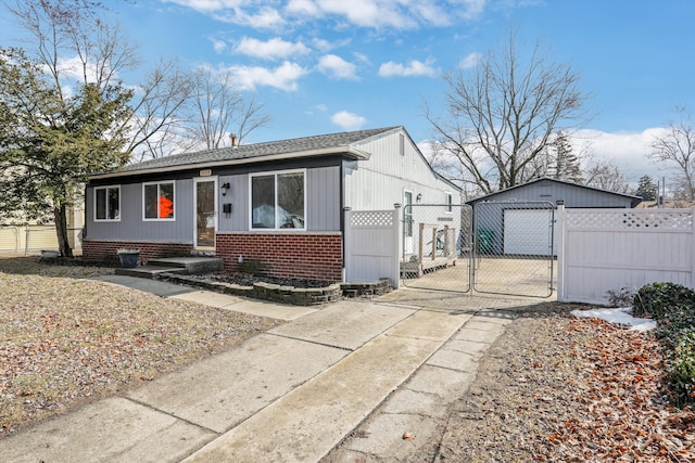 view of front of home featuring a garage, a gate, fence, an outdoor structure, and brick siding