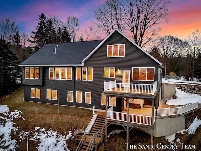 snow covered rear of property with stairway and a wooden deck