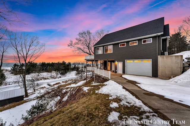 view of snowy exterior featuring a garage and driveway