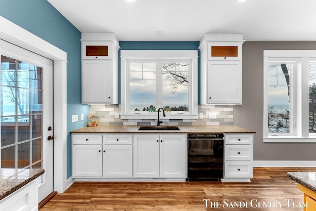 kitchen featuring a wealth of natural light, black dishwasher, white cabinets, and a sink