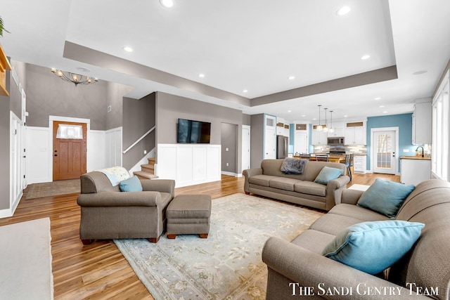 living room with light wood-style floors, recessed lighting, and a tray ceiling