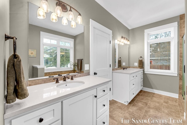 bathroom featuring tile patterned flooring, two vanities, a sink, and baseboards