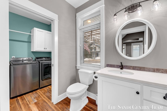 bathroom with a wealth of natural light, wood finished floors, toilet, and washer and dryer